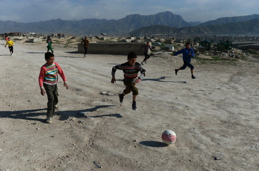 Bambini afgani giocano a pallone vicino a un cimitero sulle colline di Kabul, 12 aprile 2014