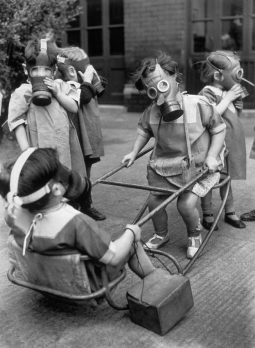 Bambini dell'asilo in un parco giochi con le maschere antigas, 1940